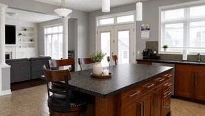 A modern kitchen with a dark granite island, wooden cabinets, and a built-in oven. - Spacious Getaway Stay w/ 4BR & 3BA| Niagara Falls (Welland)