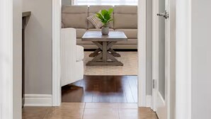 A hallway leading to a dining area with a sofa, table, and pendant light. - Spacious Getaway Stay w/ 4BR & 3BA| Niagara Falls (Welland)