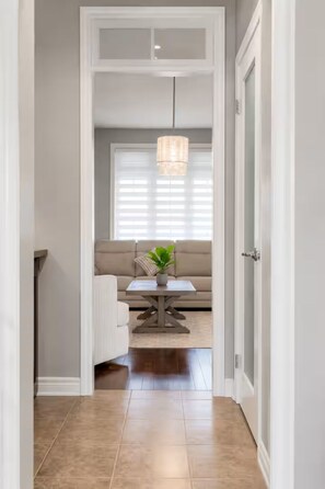 Un couloir menant à un espace repas comprenant un canapé, une table et un luminaire suspendu.