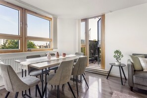 A dining area with a table, chairs, and a view through a glass door to an outdoor space. - Chelsea Riverside 4-Bed · Sleeps 10 · Workspace (Greater London)