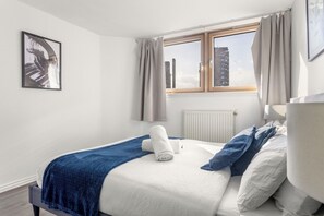 A bedroom with a bed, a window with curtains, a radiator, and a framed picture on the wall. - Chelsea Riverside 4-Bed · Sleeps 10 · Workspace (Greater London)