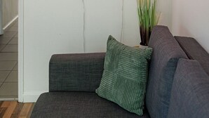 A modern living room with a gray sofa, a green pillow, and two heart-shaped neon lights on the wall. - Cozy Flat Near Station and Local Parks (London)