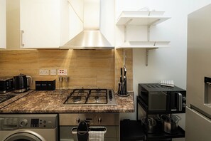 Eine moderne Küche mit Gasherd, Kaffeemaschine, Toaster und Waschmaschine.