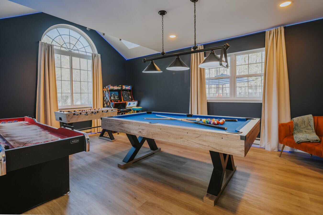 A room with a pool table, foosball table, and arcade games.