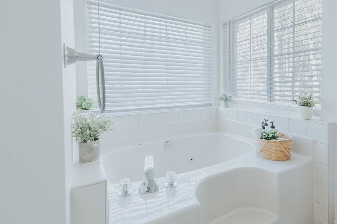 Un baño moderno con una bañera independiente, azulejos blancos y plantas en macetas.