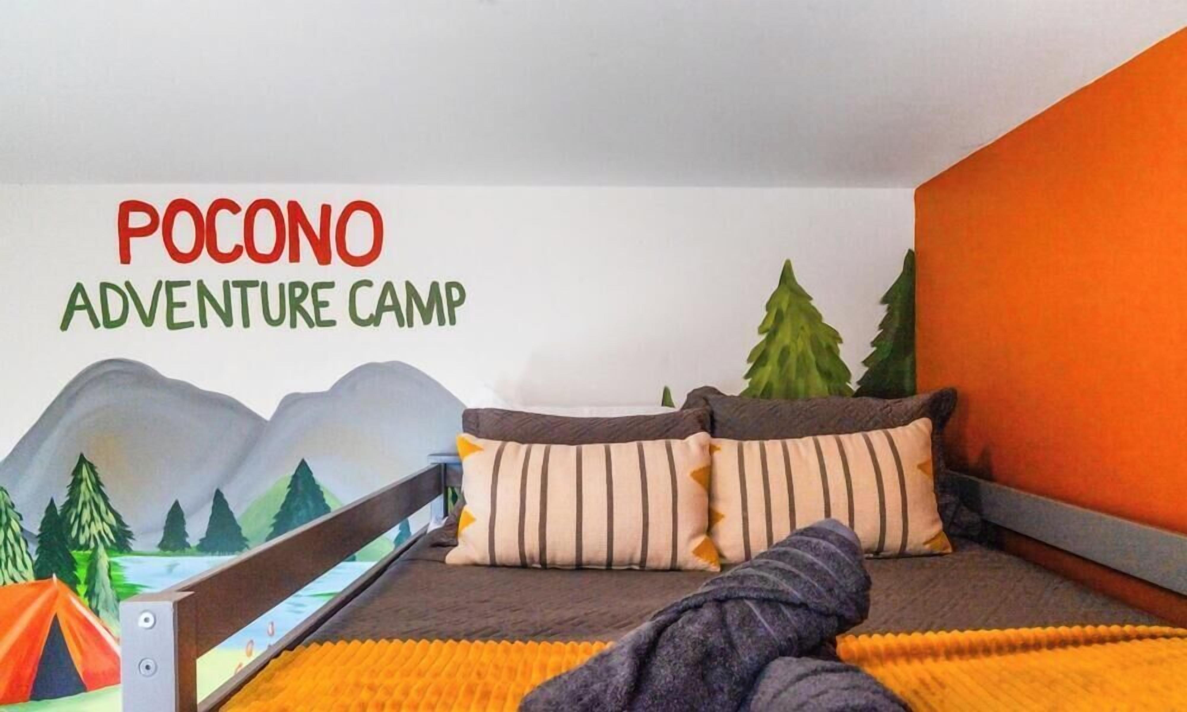 Un dormitorio con cama, almohadas, una manta, decoración tipo tienda de campaña y un mural en la pared.