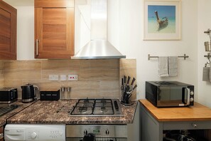Eine kleine Küche mit Gasherd, Mikrowelle, Toaster und Kaffeemaschine.
