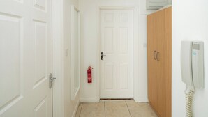 Ein Flur mit weißen Türen, einem Feuerlöscher, einem Holzschrank und einem an der Wand montierten Telefon.