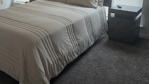 Une chambre à coucher avec un lit, deux tables de chevet et un sol recouvert d’une moquette.