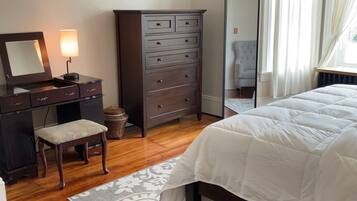 A bedroom with a bed, a dresser, a mirror, a desk, and a chair.