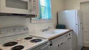 A compact kitchen with a microwave, stove, sink, and refrigerator.