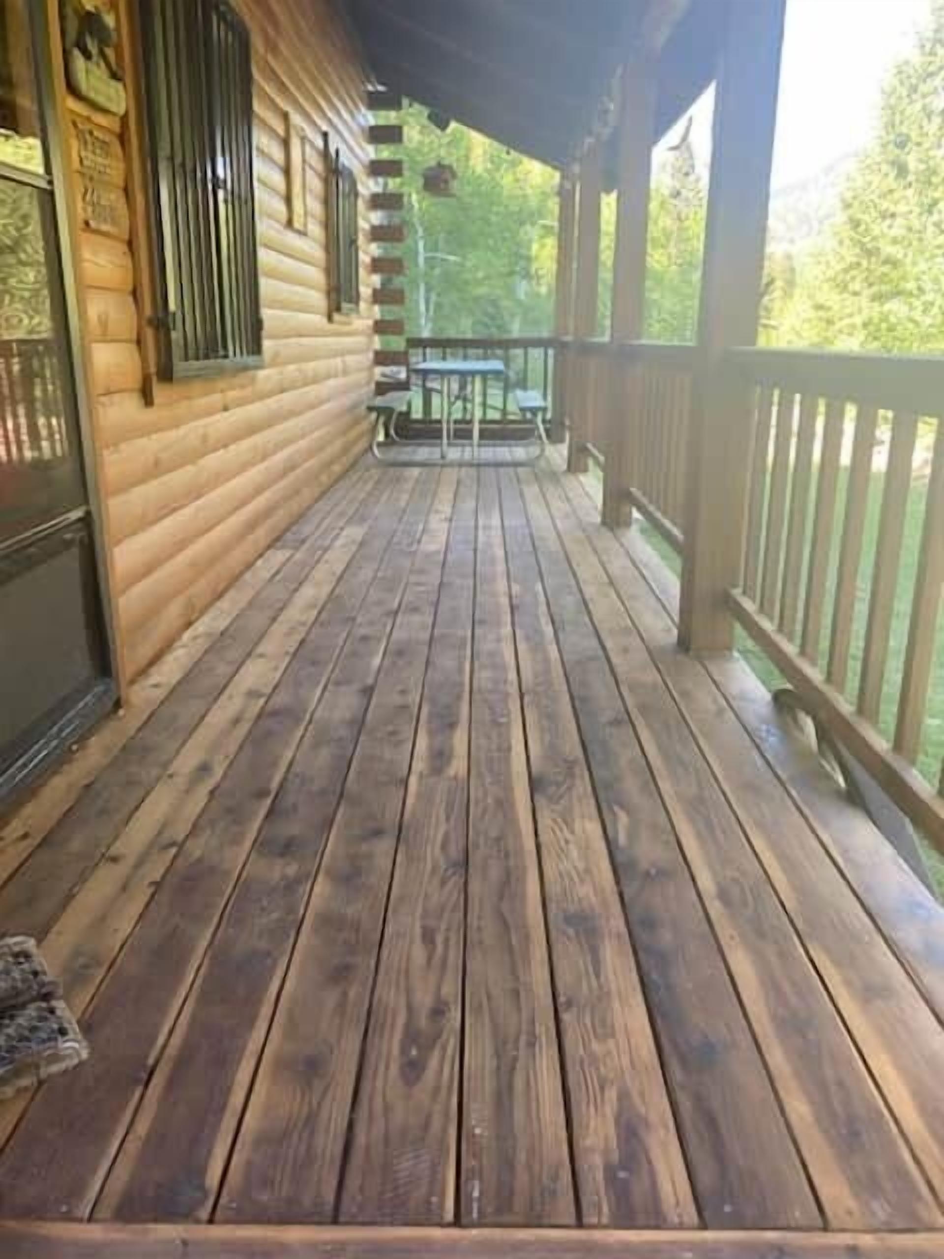 Une terrasse en bois avec une rambarde, une table et un banc.