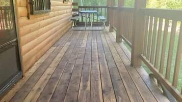 Une terrasse en bois avec une rambarde, une table et un banc.