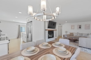 A modern kitchen with a dining area, a fireplace, and a living room with a sofa and coffee table. - Summer Retreat with Pool & Views - Sleeps 8! (Tucson)