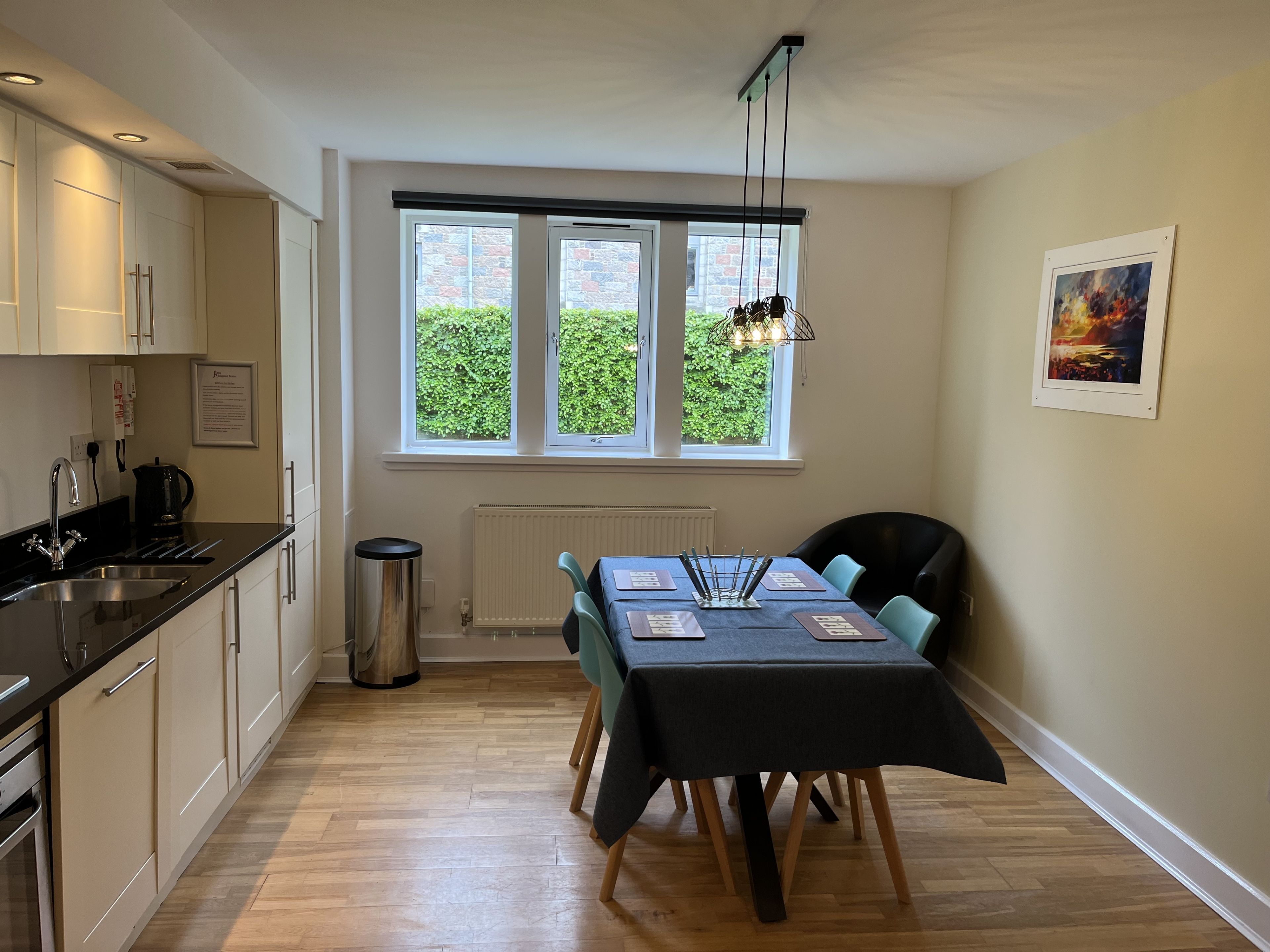 Una cocina moderna con comedor, una ventana con vistas a zonas verdes y un radiador.