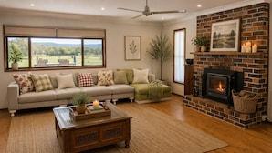Uma sala de estar com sofá, lareira, mesa de centro e vista para o exterior.