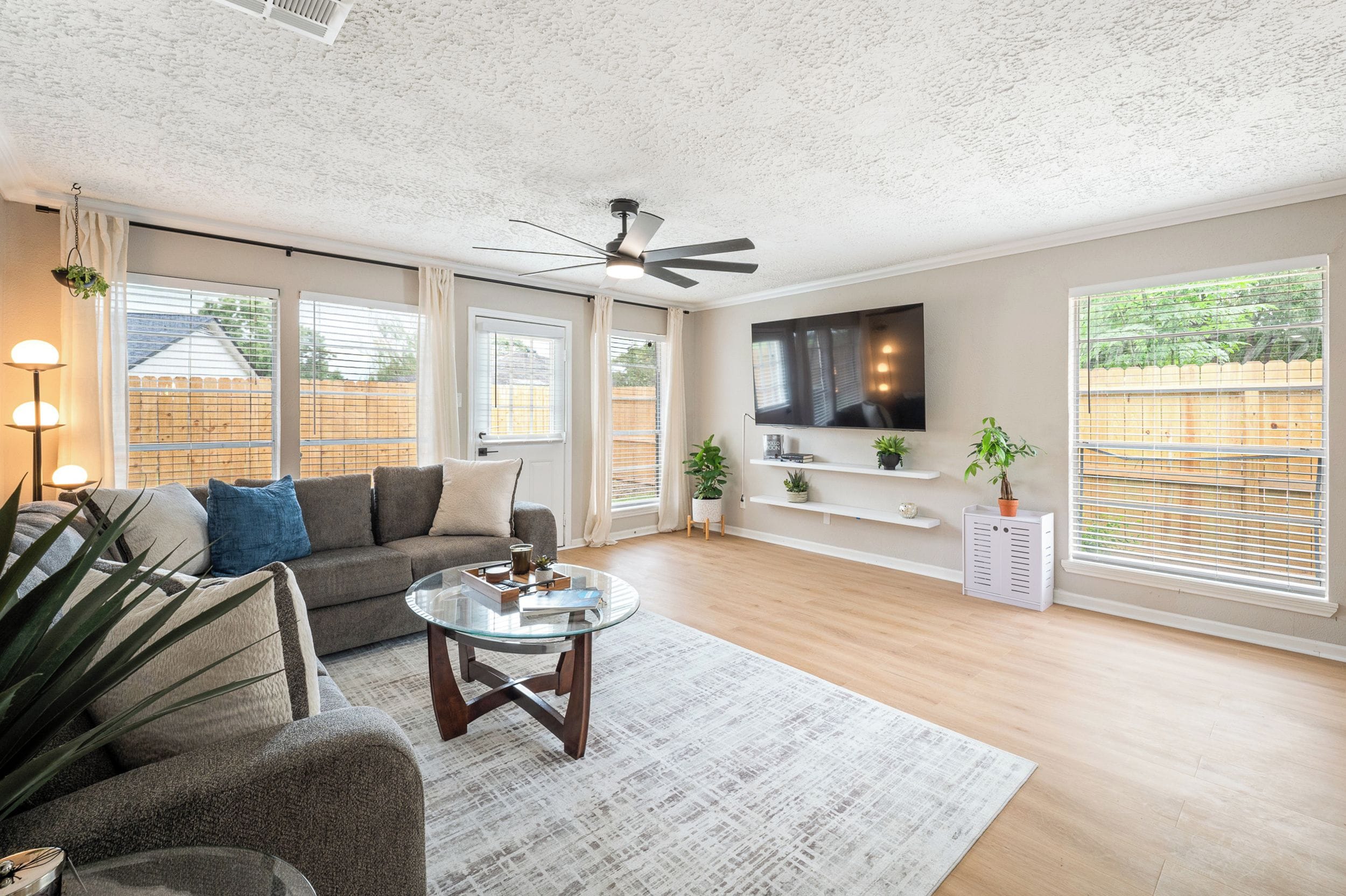 A modern living room with a sofa, coffee table, TV, and large windows.