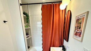 A bathroom with a toilet, sink, shower, and a radiator.