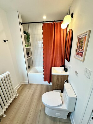 Ein Badezimmer mit Toilette, Waschbecken, Dusche und Handtuchheizkörper.