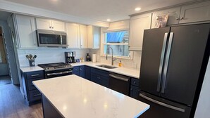 Una cocina moderna con una isla central, electrodomésticos de acero inoxidable y una ventana sobre el fregadero.