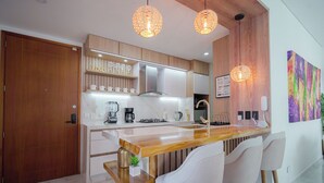 Eine moderne Küche mit Holzschränken, einer Marmorarbeitsplatte und Pendelleuchten.