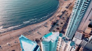 An aerial view of a coastal area with a beach, parking lot, and high-rise buildings. - MODERN BEACHFRONT APARTMENT IN BOCAGRANDE, CARTAGENA DE INDIAS⛱️🌴 (Cartagena de Indias)