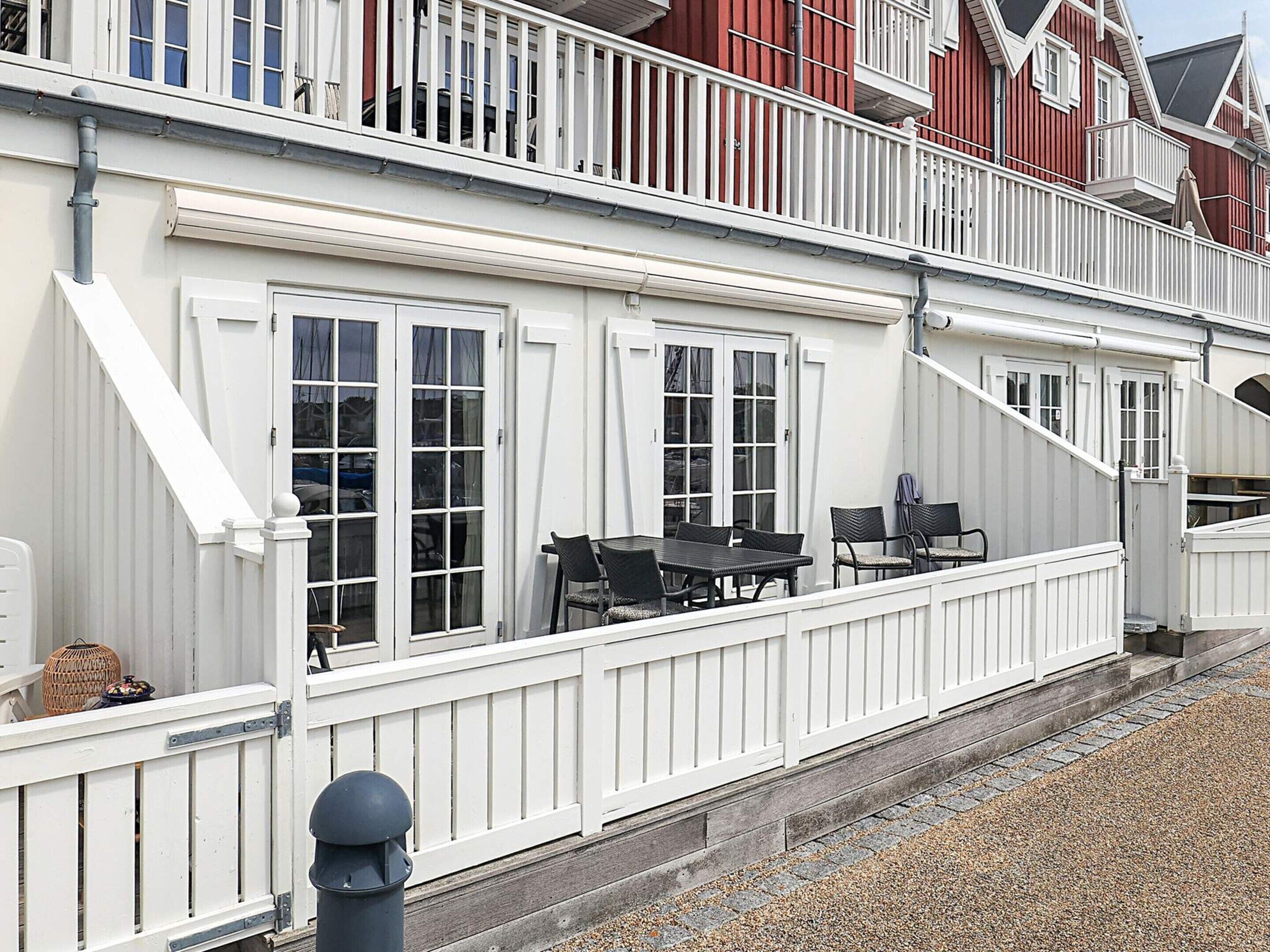 A white building with a balcony, a table with chairs, and a covered outdoor seating area.