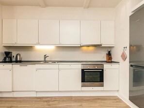 Uma cozinha moderna com armários brancos, um forno Bosch e uma cafeteira.