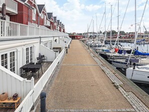 Marina com barcos atracados, calçada de cascalho e edifícios com varandas.