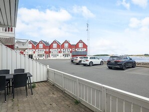 Um hotel costeiro com edifícios vermelhos e brancos, uma área de estacionamento com vários carros e vista para o mar.
