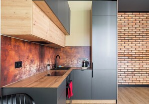 Eine moderne Küche mit Holzausziehtisch, Spüle, Kaffeemaschine und grauen Schränken.