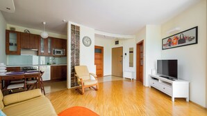 Een moderne woonkamer met een bank, een televisie en een eethoek met een tafel en stoelen.