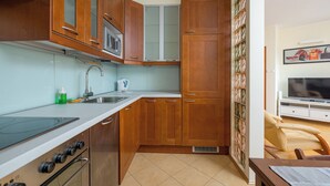 Een keuken met houten kastjes, een magnetron, een fornuis en een spoelbak.