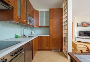 A kitchen with wooden cabinets, a microwave, a stove, and a sink. - Grodkowska Standard Apartment (Warszawa)
