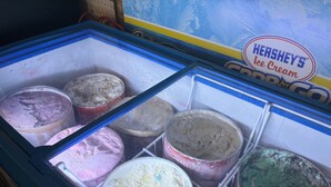Een vriezer met meerdere bakken ijs, waarvan sommige het merk Hershey's Ice Cream dragen.