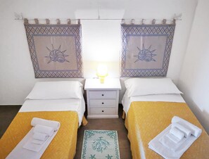 Ein Doppelzimmer mit zwei Betten, einem Nachttisch und einer Lampe.