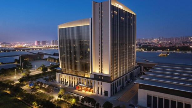 Un hotel moderno con un diseño vertical llamativo, grandes ventanales y un área de entrada bien iluminada.