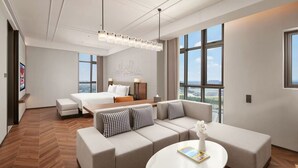 Una habitación de hotel moderna con una cama grande, un sofá, una mesita de centro y vistas a la ciudad.