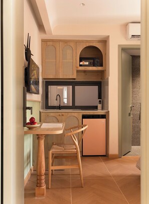 Una cucina compatta con forno a microonde, un piccolo frigorifero e un'area pranzo con tavolo e sedia in legno.