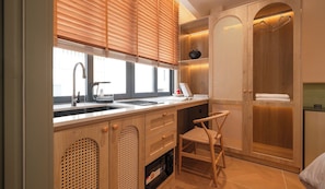 A modern bathroom with a wooden vanity, a sink, a shower with a wooden door, and a chair. - Phuc Loc Premier (Ben Thanh)