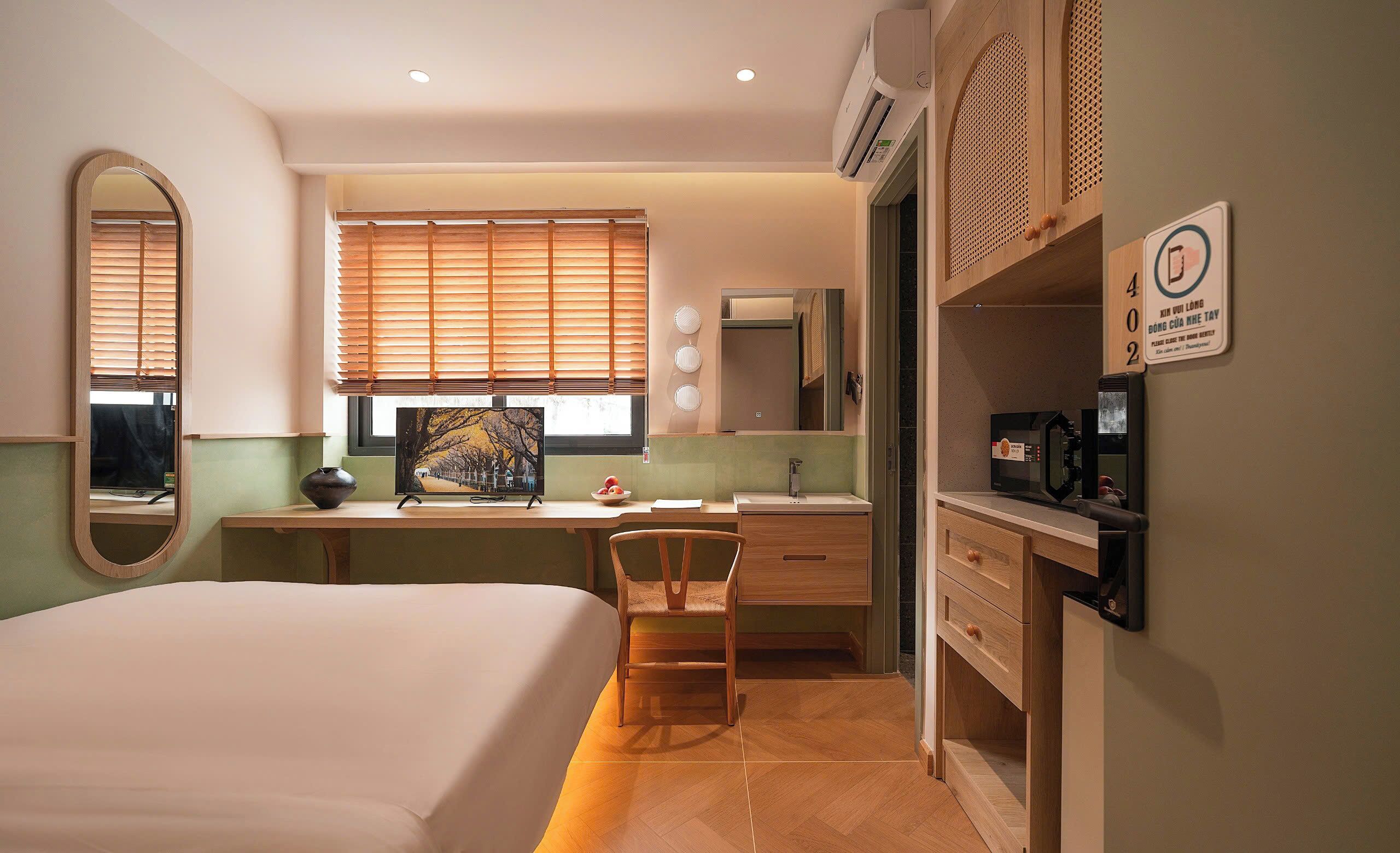 Une chambre d’hôtel comprenant un lit, un bureau, une chaise et une salle de bain avec un miroir et un lavabo.