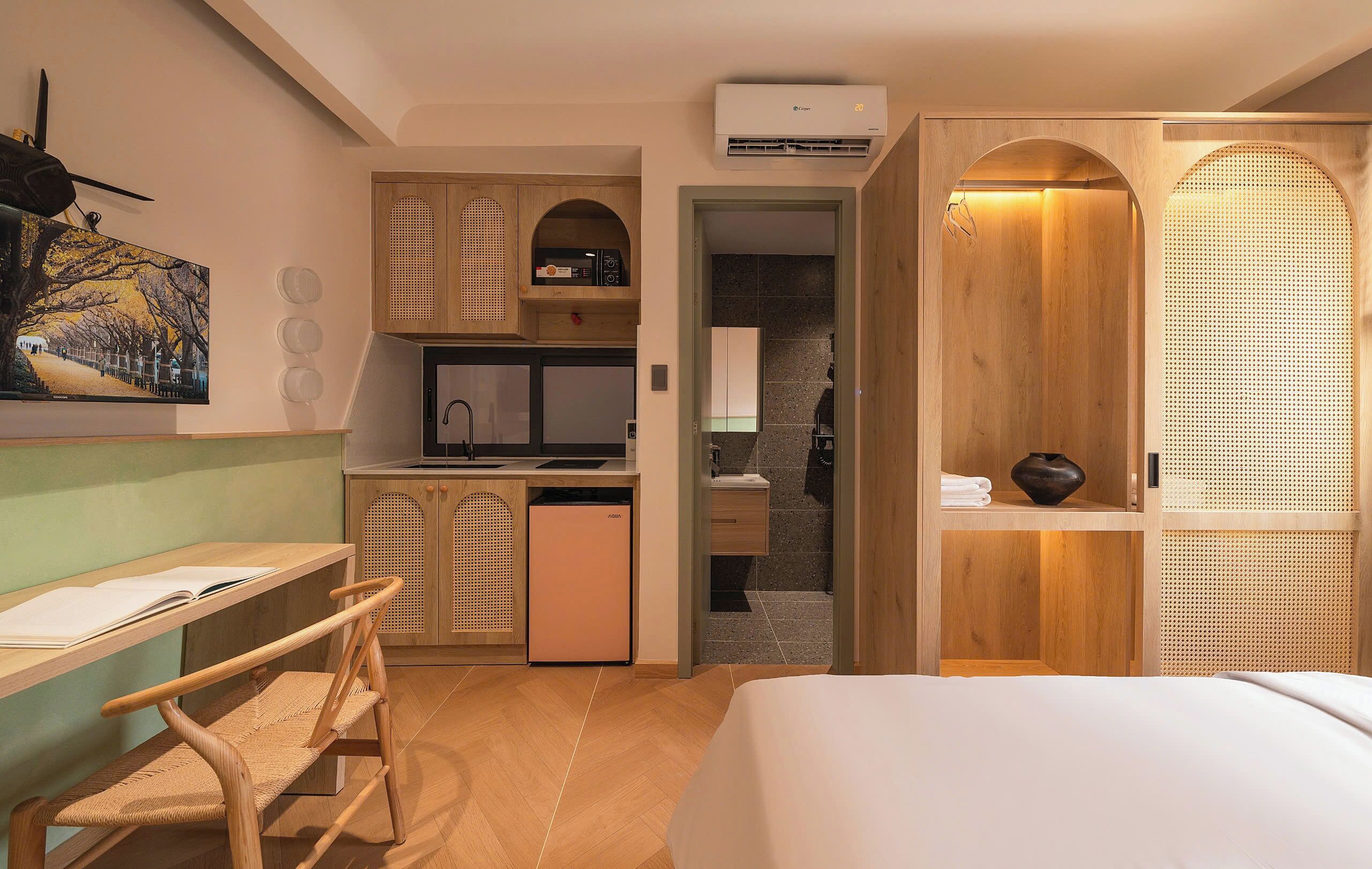 Una camera d'albergo compatta con un letto, una scrivania, angolo cottura e bagno.