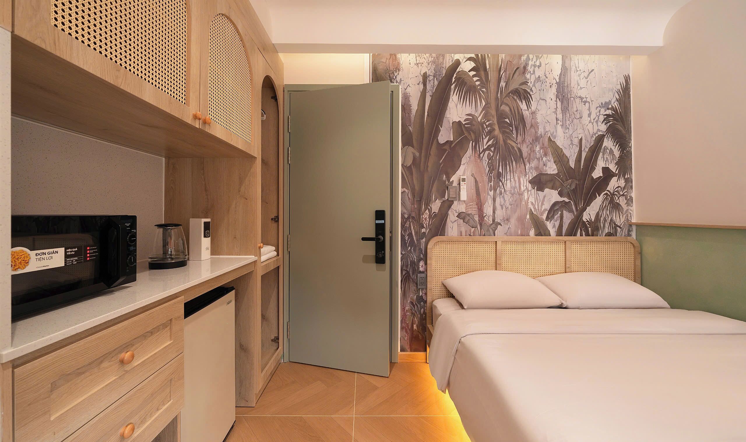 Habitación de hotel con cama, microondas, cafetera y puerta que da a otra habitación.