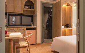 A compact hotel room with a kitchenette, a shower, a bed, and a small table with chairs. - Phuc Loc Premier (Ben Thanh)