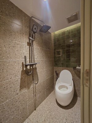 Un bagno moderno con doccia, servizi igienici e piastrelle verdi.