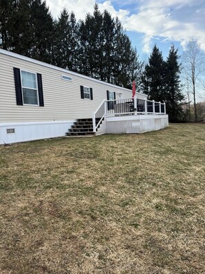 Une maison mobile dotée d’une terrasse, d’un patio couvert et d’un espace clôturé.