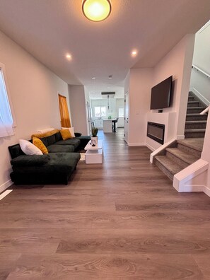 Ein modernes Wohnzimmer mit Sofa, Couchtisch und Wandfernseher.