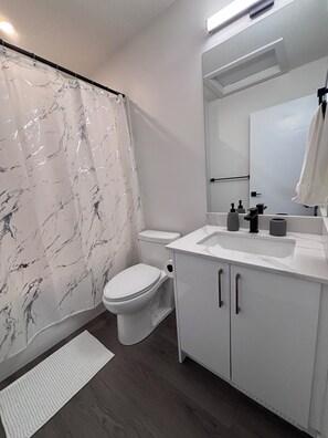 Une salle de bain moderne équipée de toilettes, d’un lavabo et d’un rideau de douche.