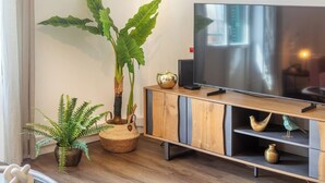 Ein modernes Wohnzimmer mit Fernseher, Holzschrank und Zierpflanzen.
