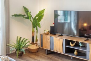 Ein modernes Wohnzimmer mit Fernseher, Holzschrank und Zierpflanzen.